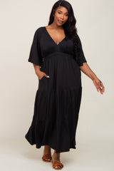 woman wearing a black tiered maxi dress with a deep v-neck and short sleeves, featuring pockets
