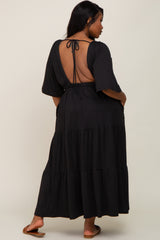 woman wearing a black tiered maxi dress with a deep back cutout and short sleeves, styled casually