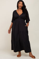 woman wearing a black plus size tiered maxi dress with a deep v-neck and pockets