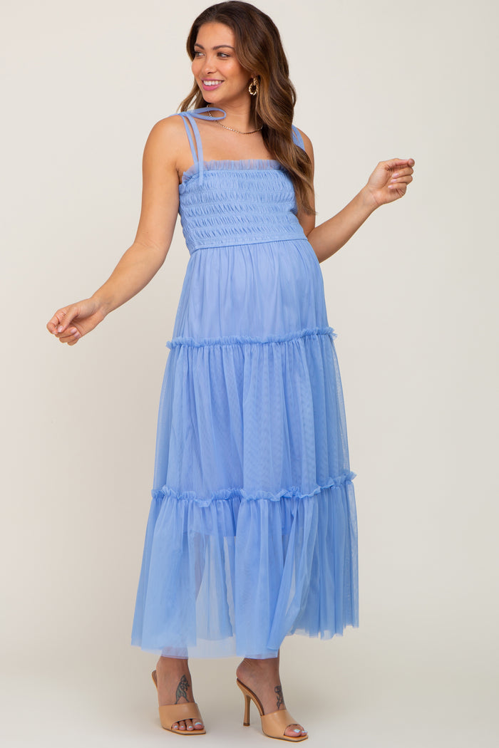 woman wearing a light blue tiered maternity dress with smocked bodice and spaghetti straps, showing her baby bump