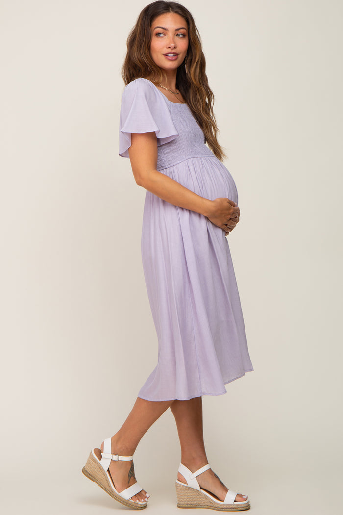 woman wearing a lavender maternity dress with flutter sleeves and a visible baby bump