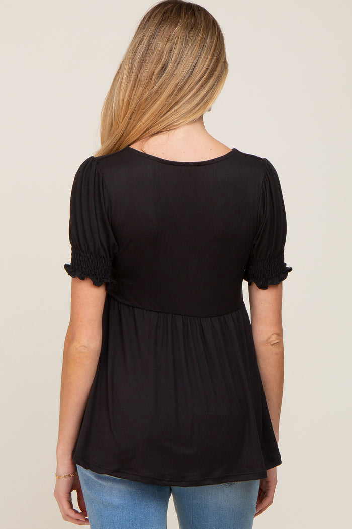 woman wearing a black maternity top with short puff sleeves and a flowy silhouette