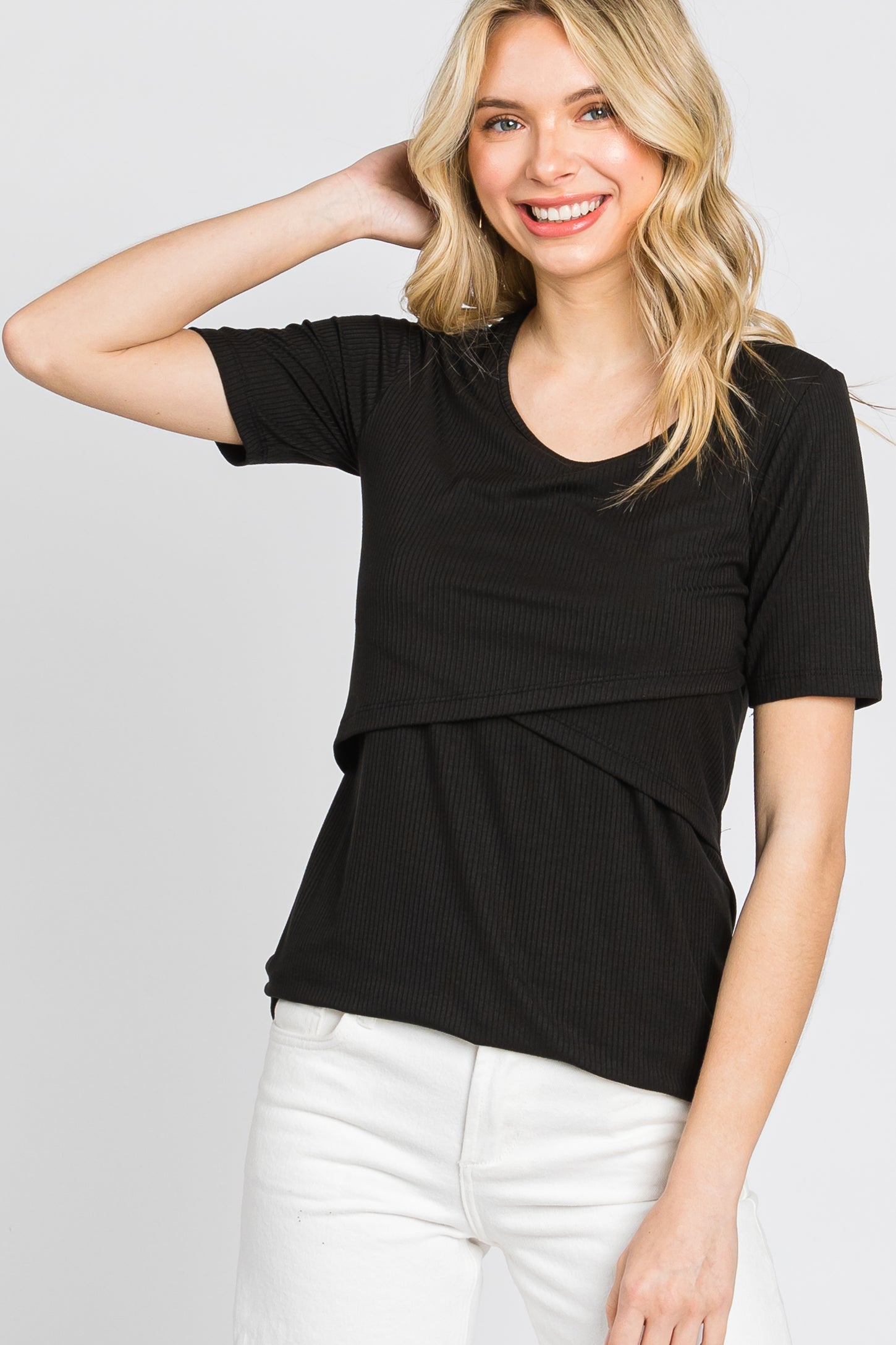 woman wearing a black ribbed short sleeve top with a layered design and smiling