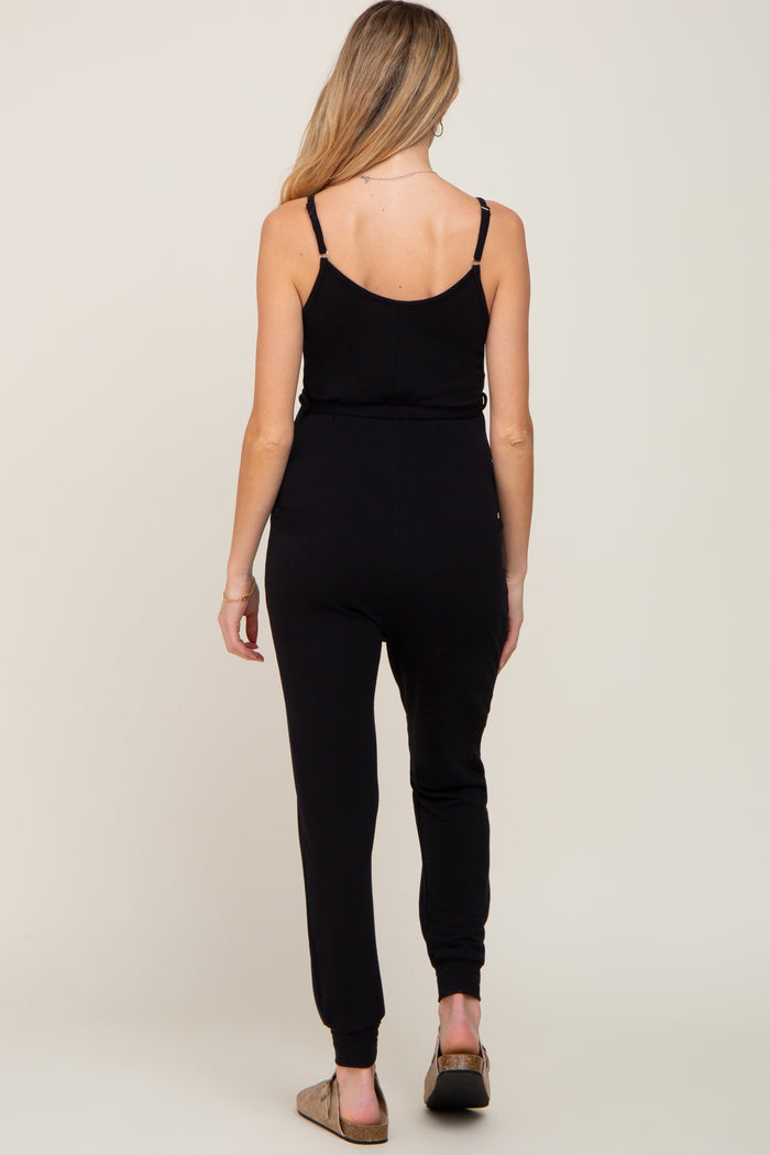 woman wearing a black maternity jumpsuit with fitted legs and adjustable spaghetti straps, showing her back