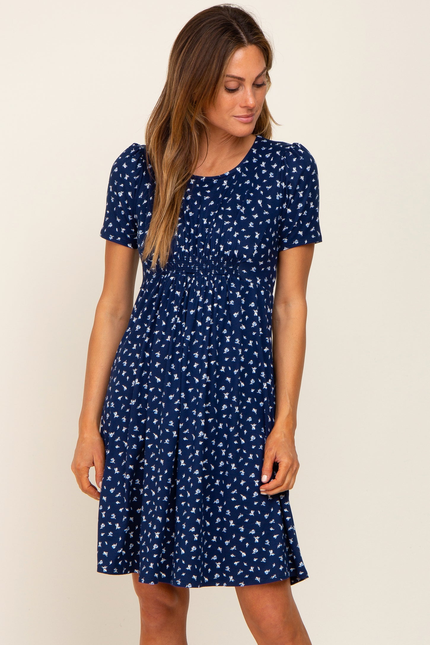 woman wearing a navy blue short sleeve floral print dress with a smocked waist