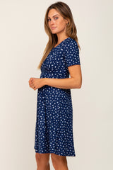 woman wearing a navy blue short sleeve dress with a floral print and a fitted bodice, standing sideways