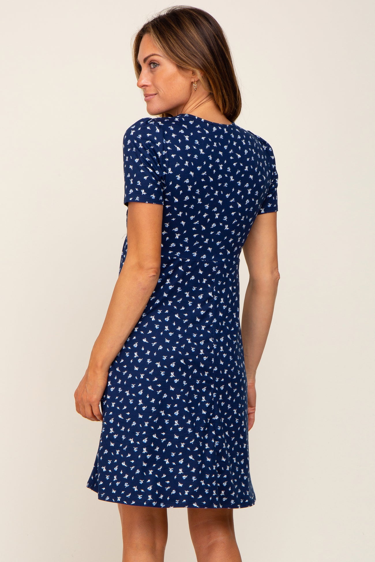 woman wearing a navy blue short sleeve dress with a white floral print and a relaxed fit, seen from the back