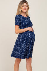 woman wearing a navy blue short sleeve maternity dress with white floral print and showing her baby bump