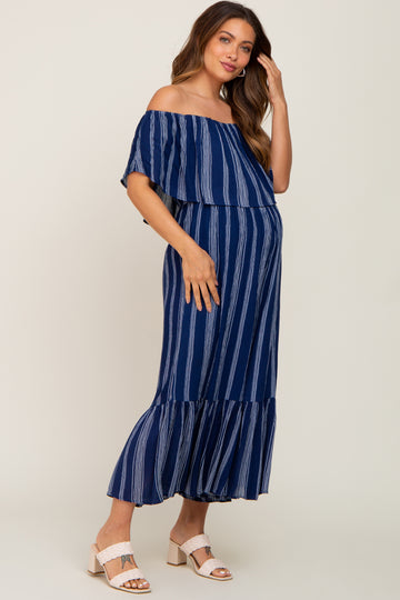 Pregnant woman wearing a navy blue and white striped off-the-shoulder maternity maxi dress with ruffled hem