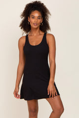 woman with curly hair wearing a black sleeveless mini dress and gold hoop earrings