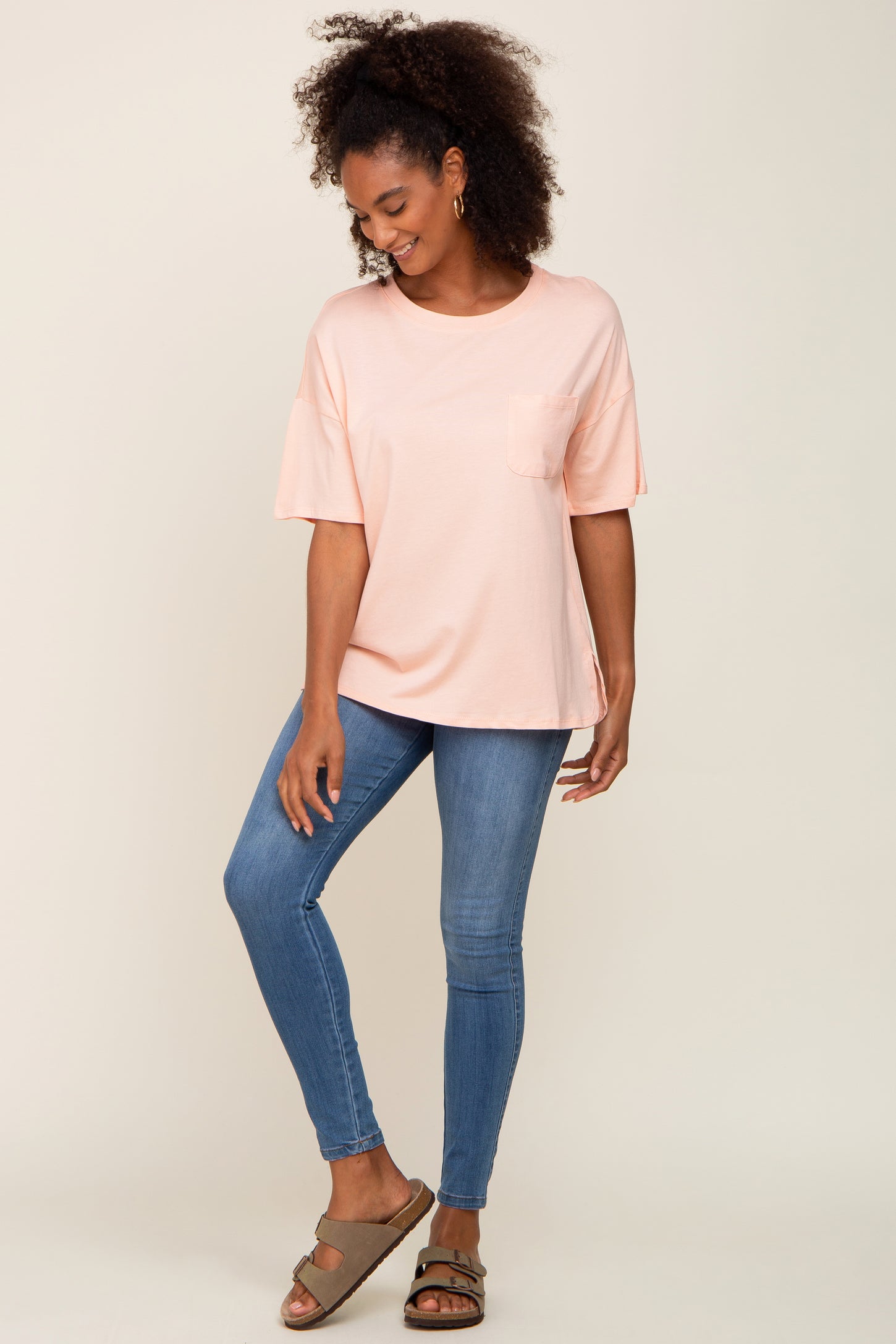woman wearing a soft pink short sleeve top with a pocket and blue skinny jeans
