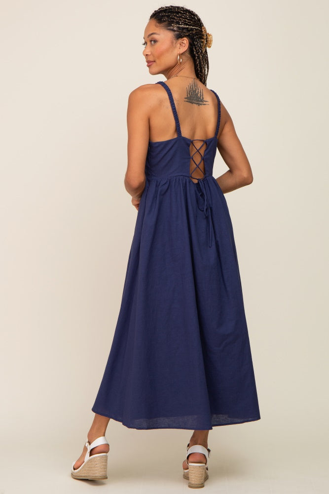 woman wearing a navy blue midi dress with lace-up back detail and white wedge sandals