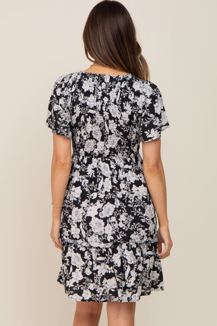 woman wearing a black floral maternity dress with short sleeves and a ruffled hem, showing her baby bump from the back
