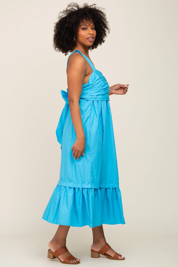 woman wearing a bright blue midi dress with a ruched bodice and tiered ruffle hem, styled with brown sandals