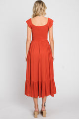 woman wearing an orange smocked back midi dress with flutter sleeves and a ruffled hem
