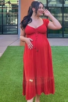 woman wearing a red maternity maxi dress with ruched detailing and a baby bump