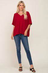 woman wearing a red v-neck oversized top with short sleeves paired with skinny jeans and sandals