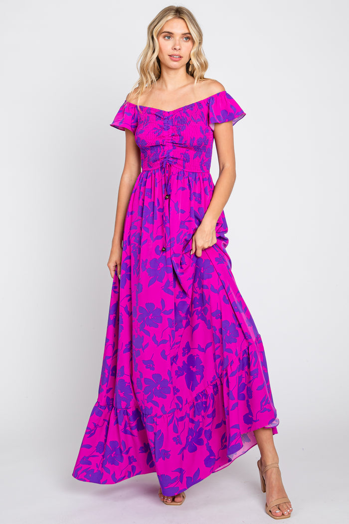 woman wearing a fuchsia and purple floral off-the-shoulder smocked maxi dress with ruffled hem