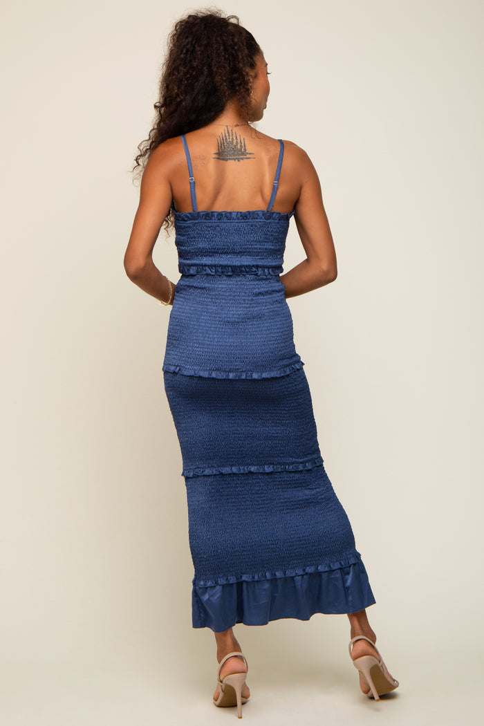 Back view of a woman wearing a blue smocked tiered maxi dress with spaghetti straps and ruffle details