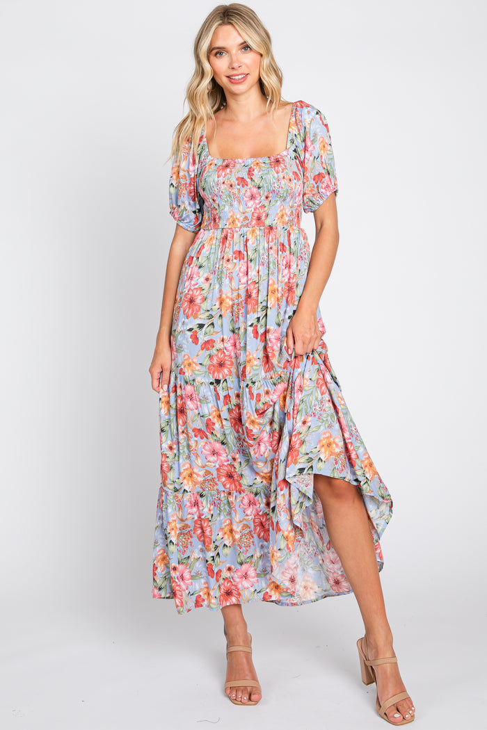 woman wearing a floral midi dress with puff sleeves and a smocked bodice, posed against a neutral background