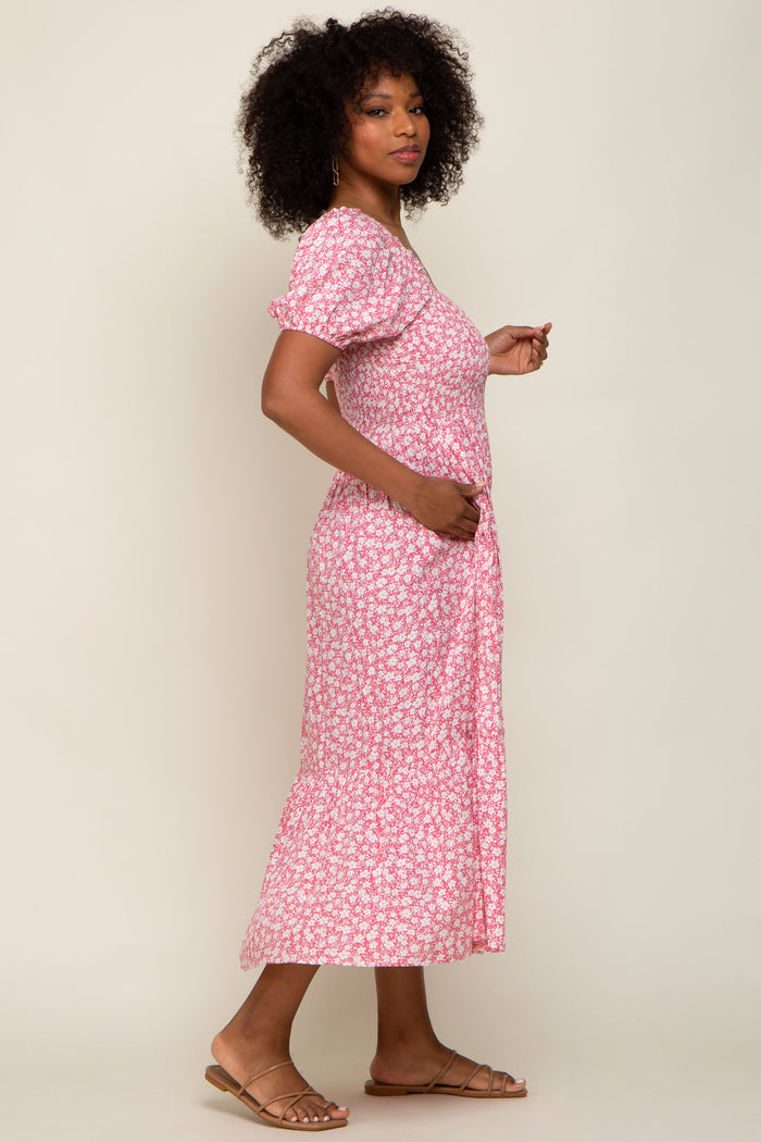 Woman with curly hair wearing a pink and white floral puff sleeve midi dress and tan sandals