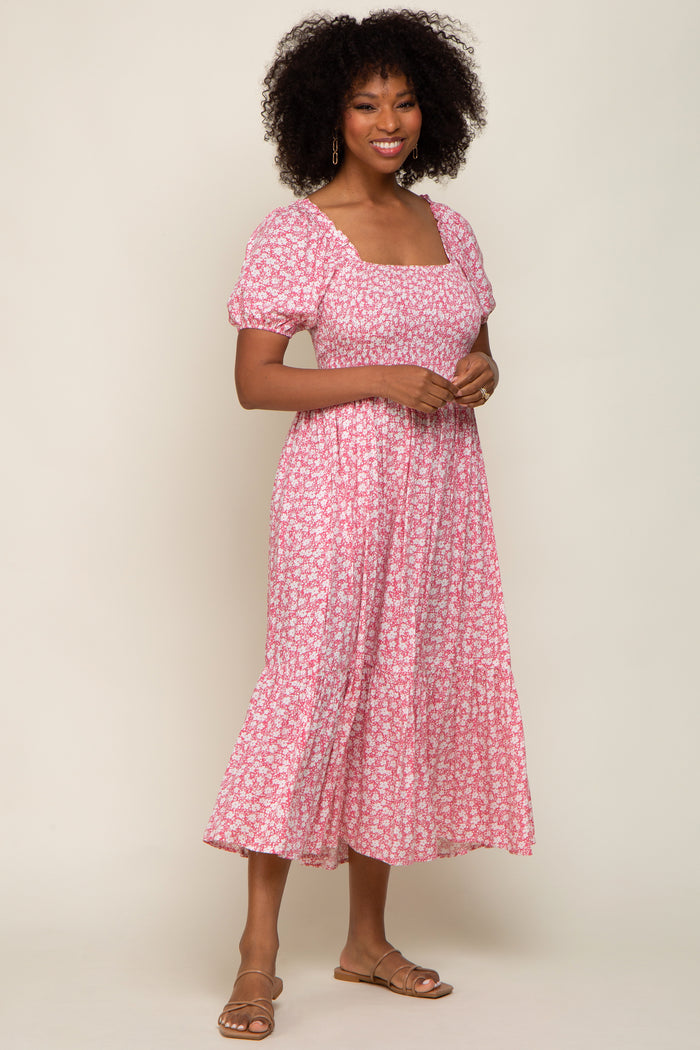 woman wearing a pink floral midi dress with puff sleeves and a square neckline, standing and smiling