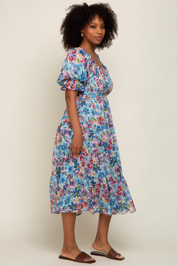 woman wearing a floral print midi dress with puff sleeves and a smocked bodice, standing against a neutral background