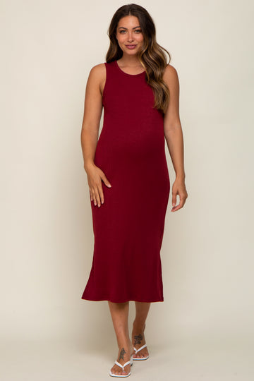 woman wearing a burgundy sleeveless ribbed maternity dress with a fitted silhouette and a baby bump visible