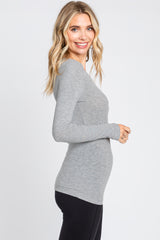 woman wearing a gray long sleeve fitted top, smiling, with side view showing a slim silhouette