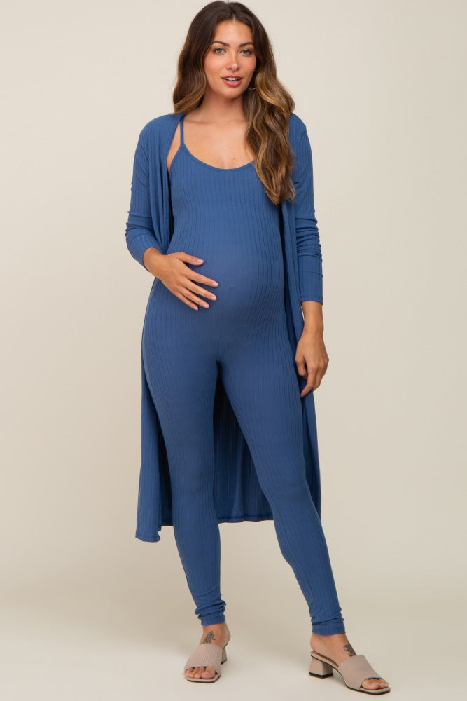 woman wearing a blue ribbed maternity jumpsuit with a long cardigan and holding her baby bump