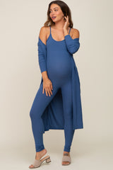 woman wearing a blue maternity ribbed jumpsuit with a matching long cardigan and showing her baby bump