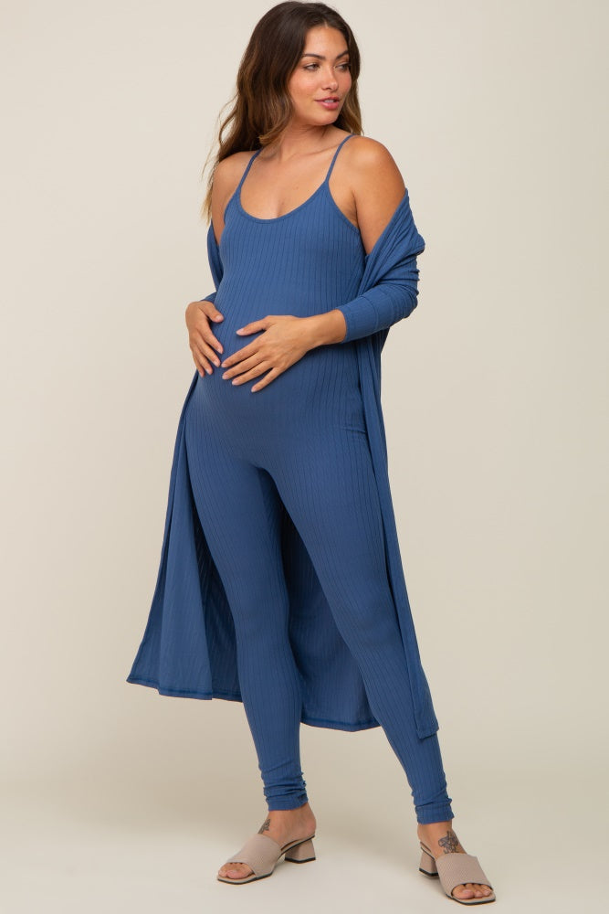 woman wearing a blue ribbed maternity jumpsuit with matching cardigan and holding her baby bump