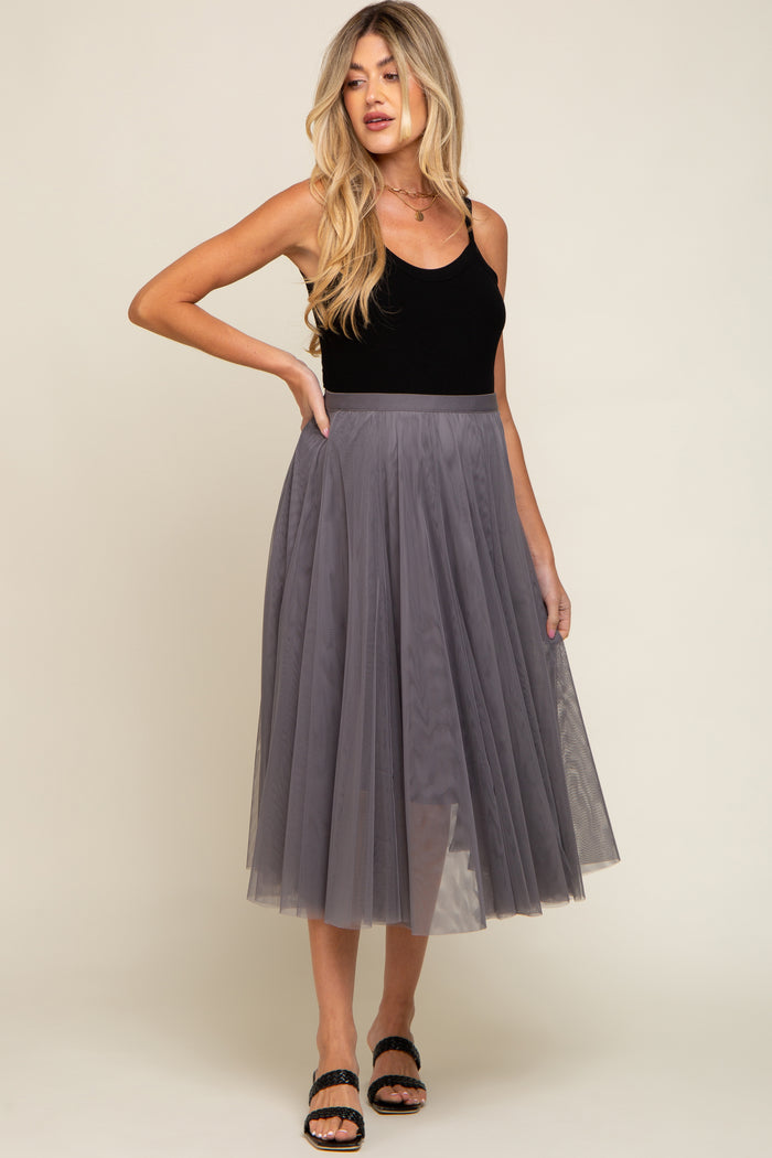 woman wearing a black tank top and a grey pleated mesh midi skirt with black sandals