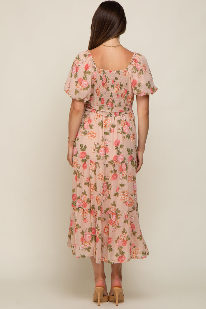 woman wearing a floral maternity maxi dress with short puff sleeves and a smocked bodice, showing a baby bump from the back