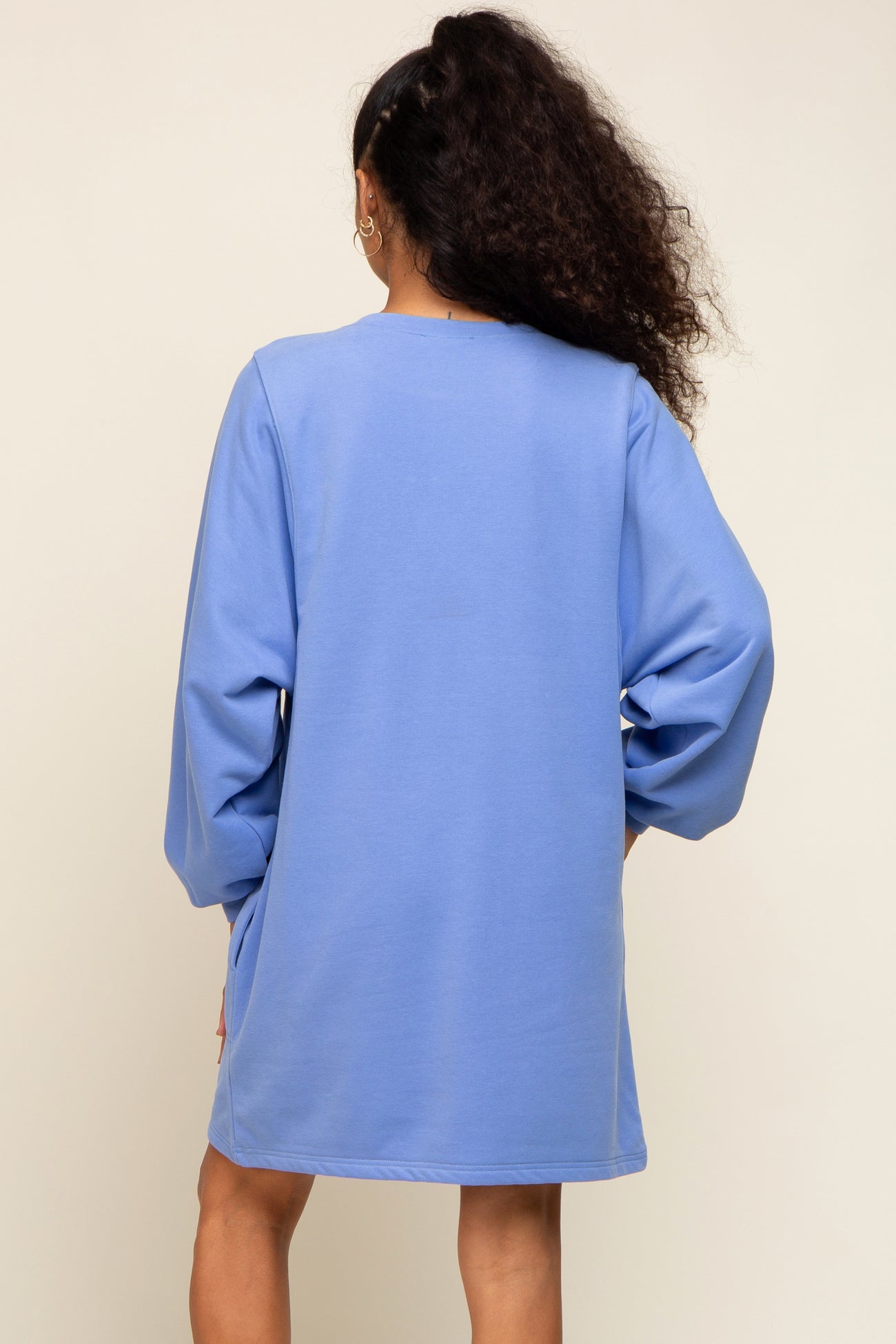 woman wearing a back view of a light blue oversized sweatshirt dress with long sleeves