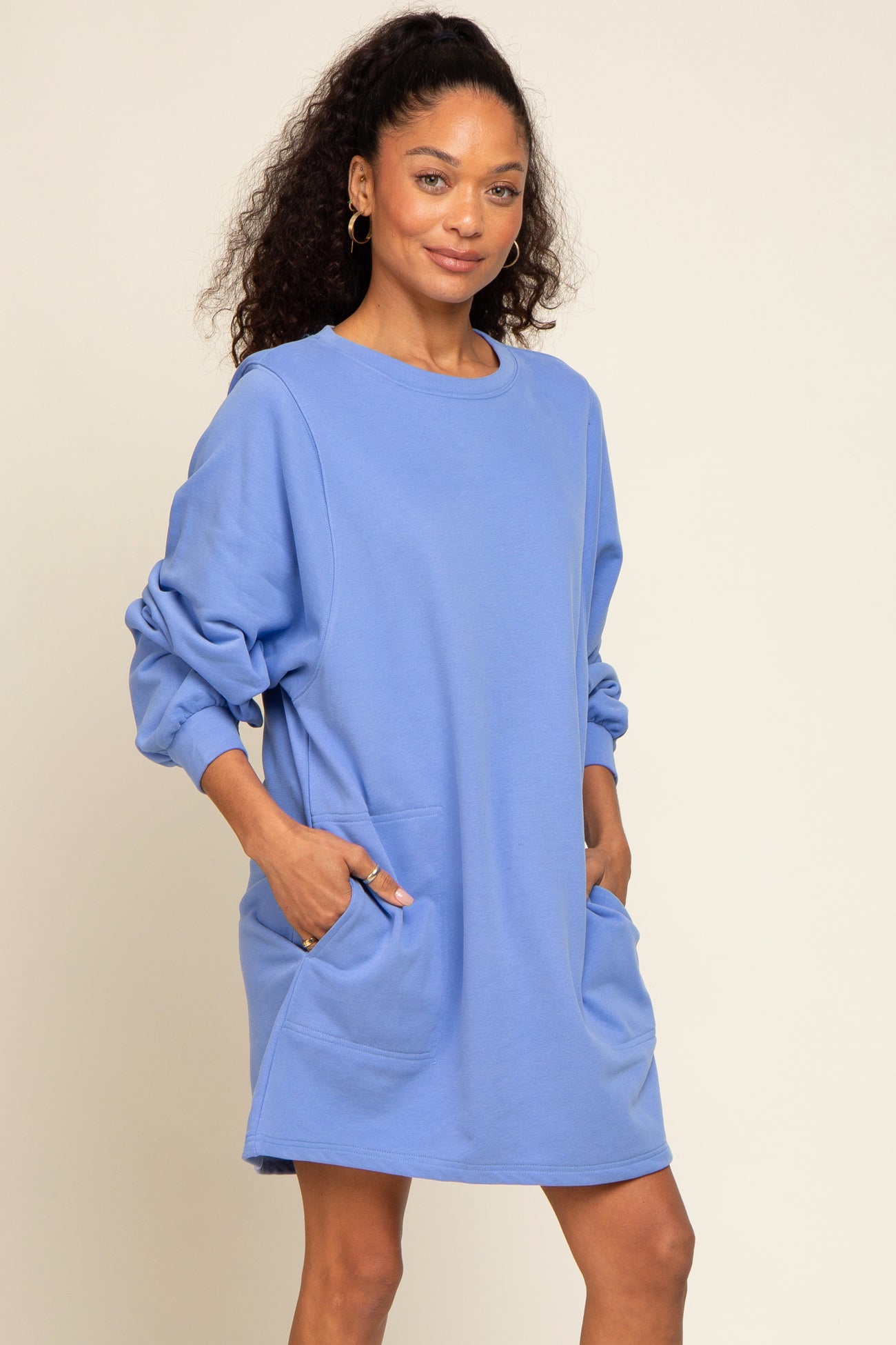 woman wearing a light blue oversized sweatshirt dress with long sleeves and side pockets