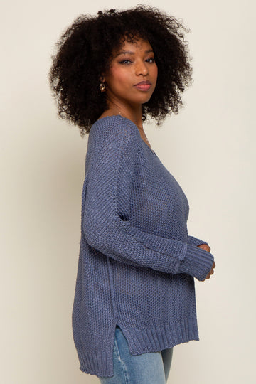 woman wearing a navy blue oversized knit sweater with side slits, paired with light wash jeans