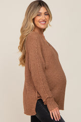 woman wearing a brown oversized maternity sweater with side slits and a visible baby bump