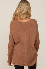 woman wearing a brown oversized maternity sweater with a loose fit and open back design