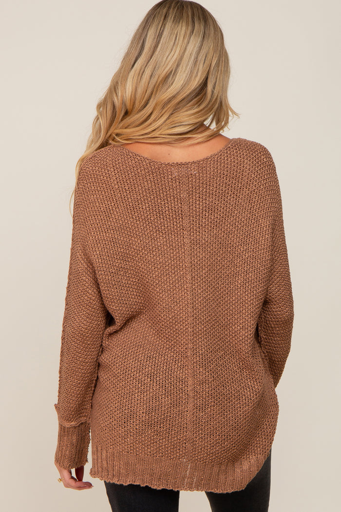 woman wearing a brown oversized maternity sweater with a loose fit and open back design