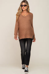 woman wearing a brown oversized maternity sweater with a v-neck, paired with black jeans and sunglasses, showing her baby bump