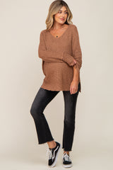 woman wearing a brown oversized knit maternity sweater and black flare jeans with sneakers