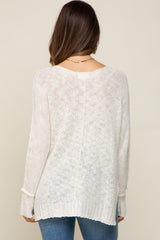 back view of a woman wearing a cream lightweight knit sweater and blue jeans