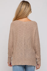 woman wearing a beige loosely knit maternity sweater with long sleeves, viewed from the back