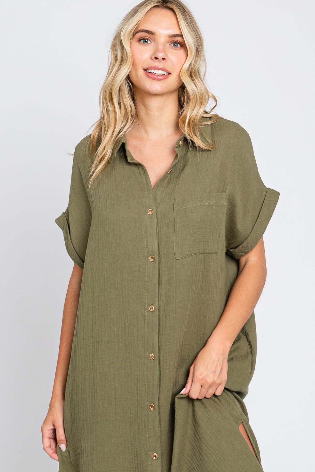 woman wearing an olive green short sleeve button-up dress with a chest pocket and side slits