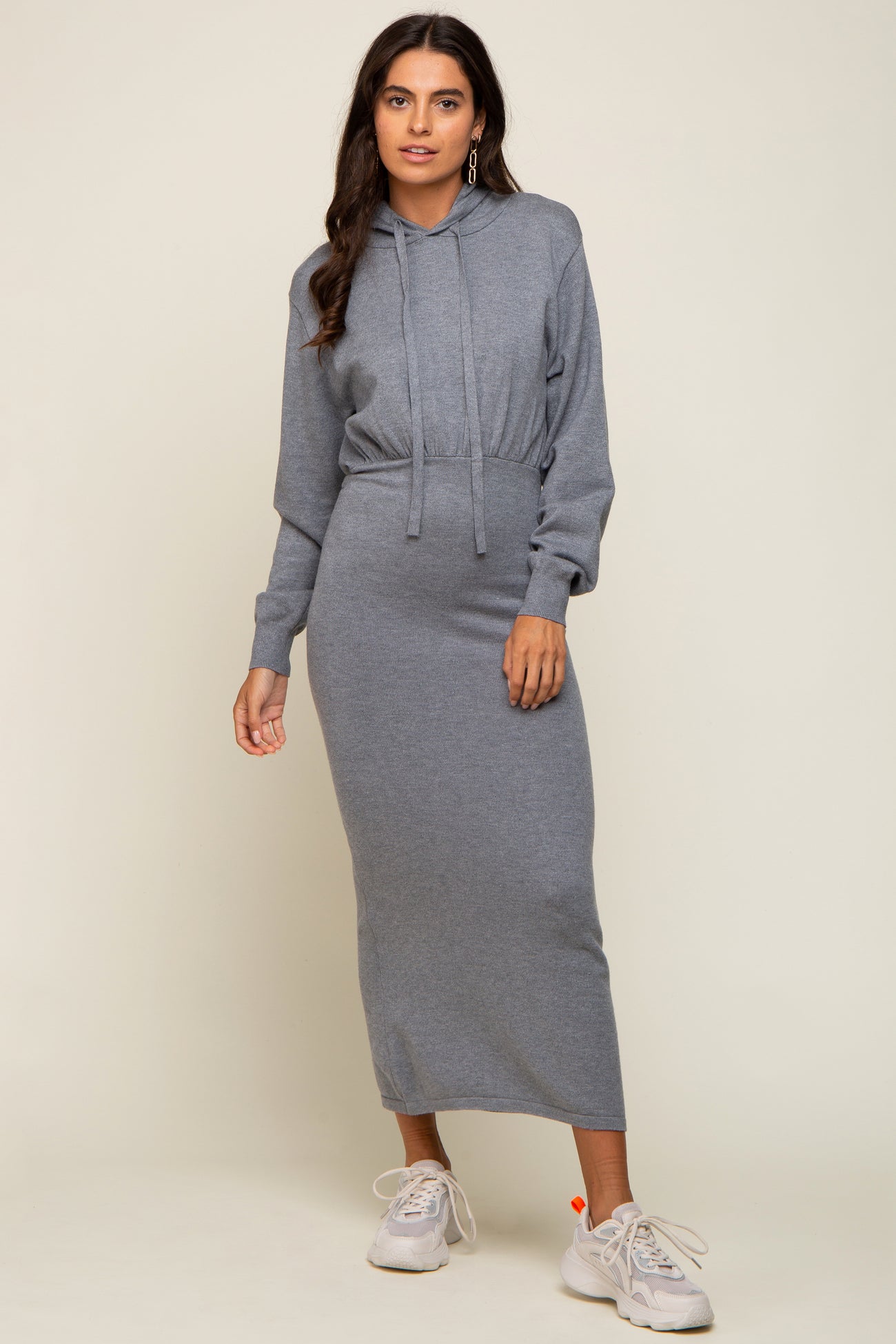 woman wearing a gray hooded long sleeve dress with a drawstring waist and white sneakers