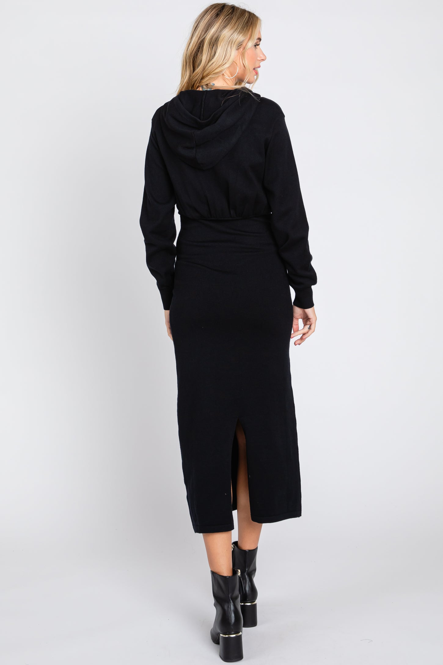 woman wearing a black hooded maxi dress with a back slit and long sleeves, seen from the back
