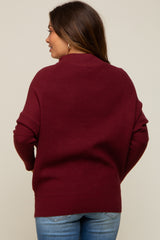 woman wearing a burgundy maternity sweater with a relaxed fit, seen from the back