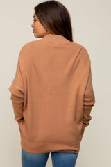 woman wearing a warm brown oversized maternity sweater, showing the back view with relaxed fit and ribbed texture