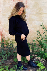 woman wearing a black long sleeve maternity dress that hugs her baby bump while standing outdoors